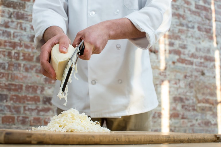 Man Hand Grates Mozzarella